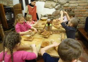 Dzieci wałkują ciasto na pierniki.